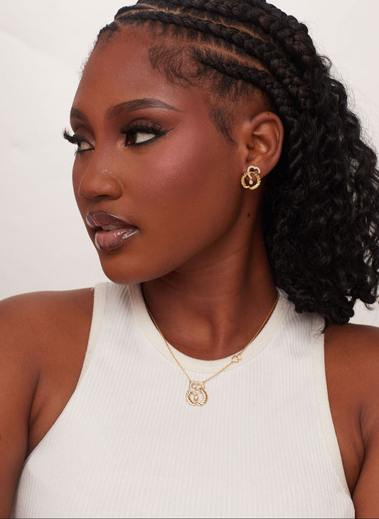 Woman with styled hair wearing gold jewelry against a white background