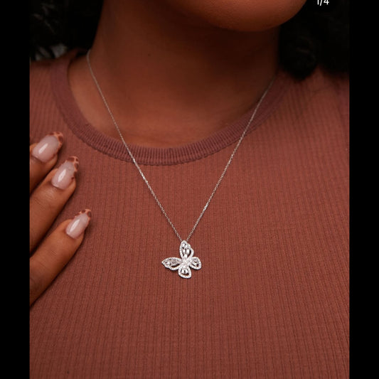 Silver butterfly necklace on a person wearing a brown top
