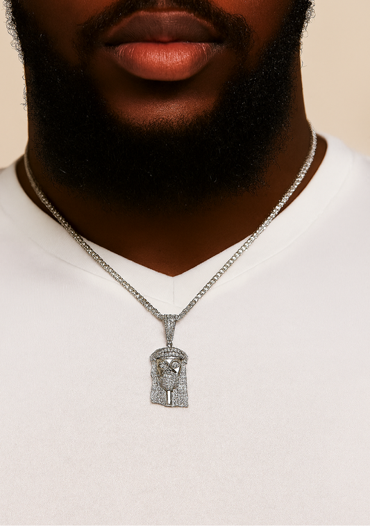 Man wearing a white shirt with a silver necklace featuring a detailed pendant against a beige background