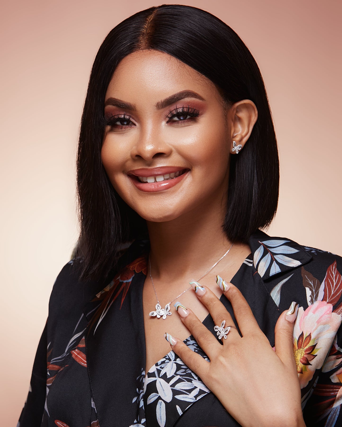 Woman wearing jewelry with a floral patterned outfit against a beige background