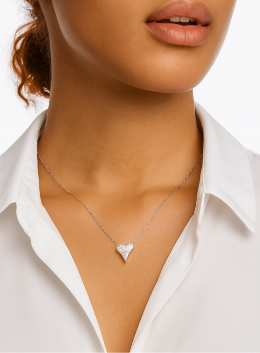 Close-up of a person wearing a silver necklace with a heart pendant.