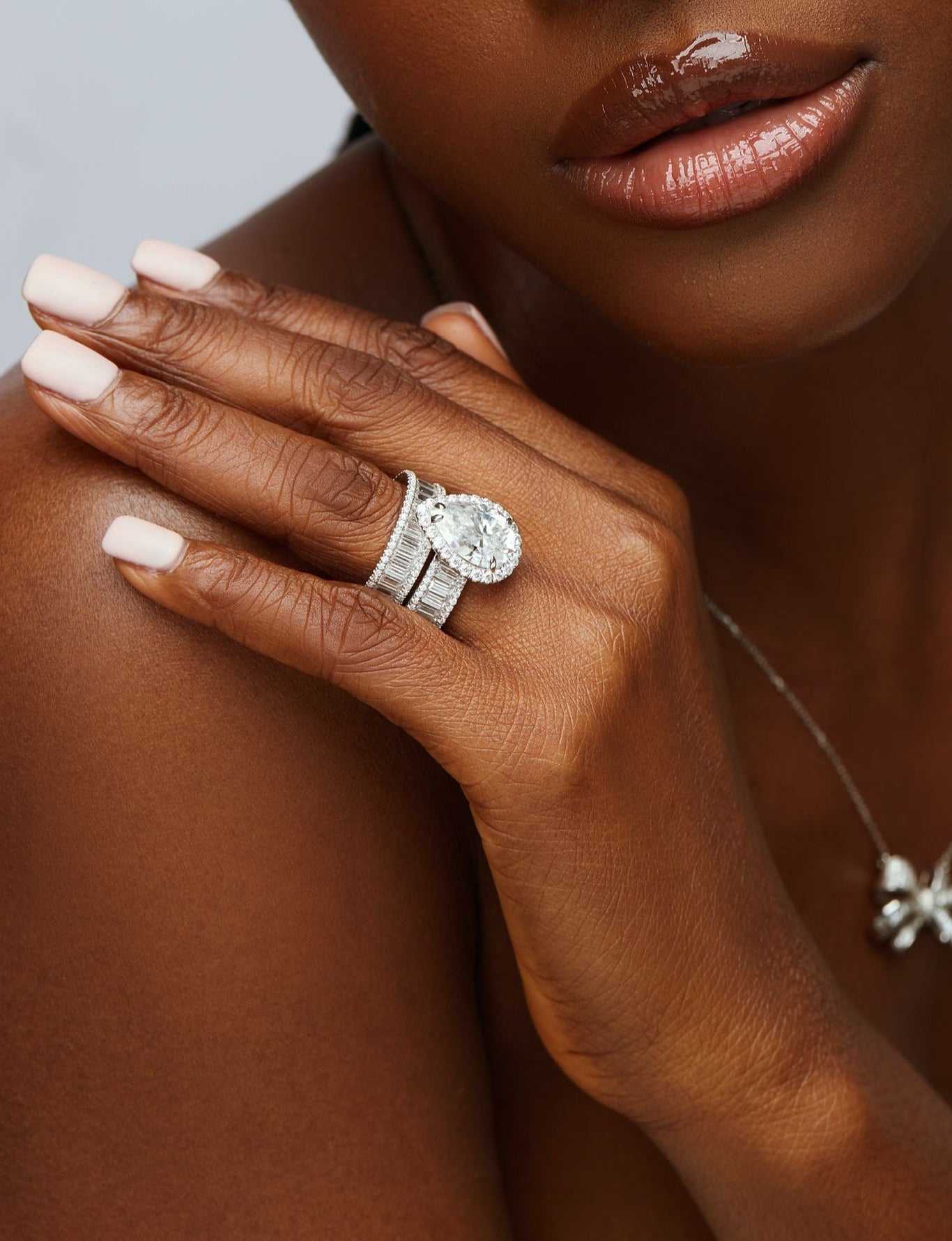 Liz Pear Cut Moissanite bride set in 18K gold on woman's hand showing pear-cut center stone and pavé accents