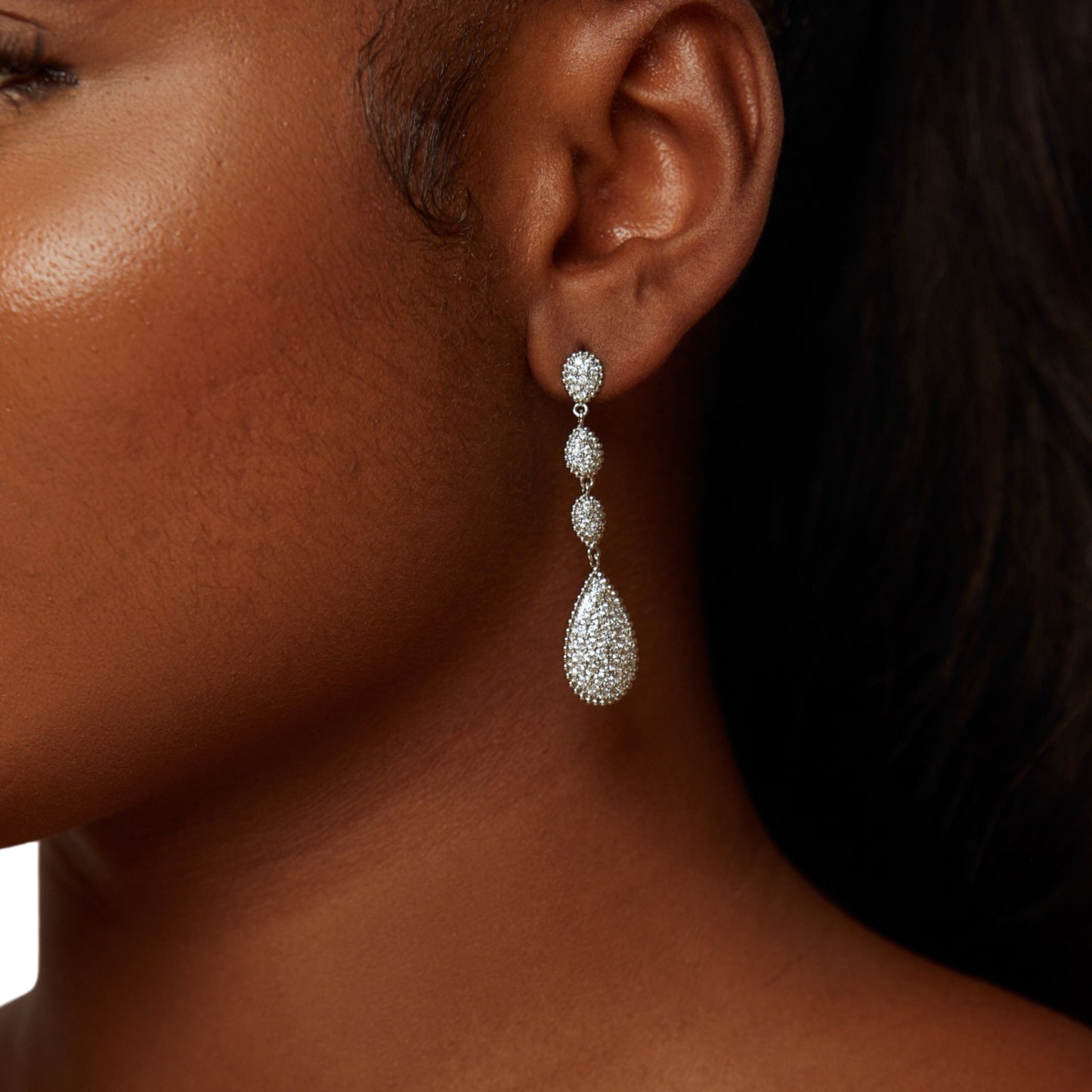 Close-up of a woman wearing a silver teardrop earring.
