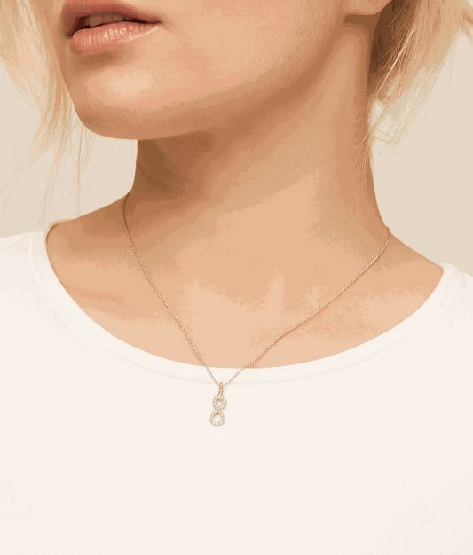 Close-up of a person wearing a delicate necklace with a small pendant on a plain background