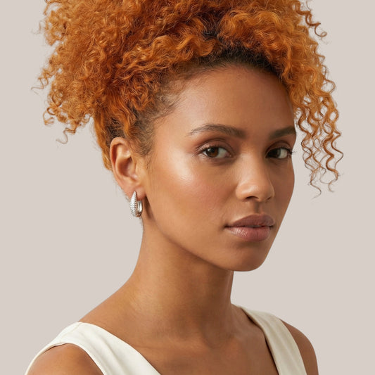 Woman with orange hair wearing a white top against a neutral background