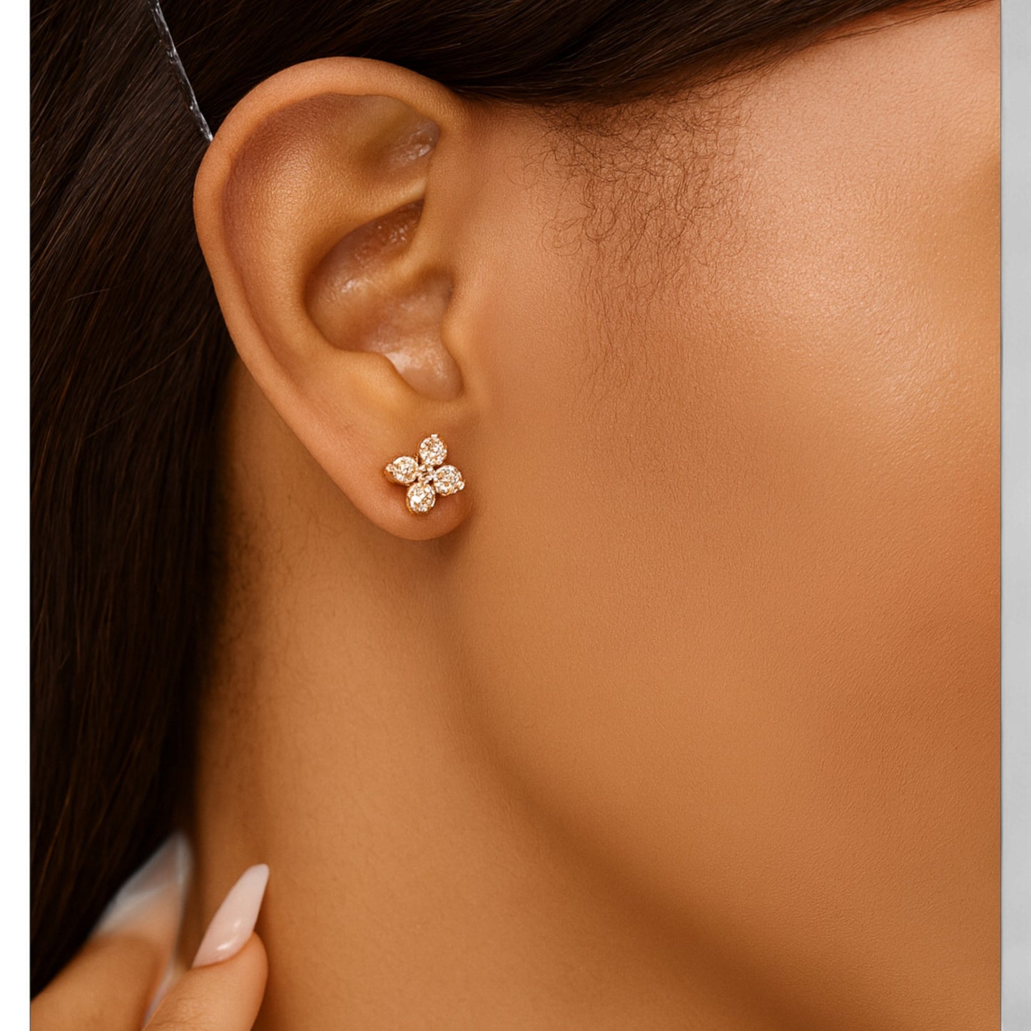 Close-up of an ear wearing a diamond earring with a neutral background