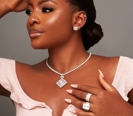 Woman wearing a pearl necklace and rings on a gray background