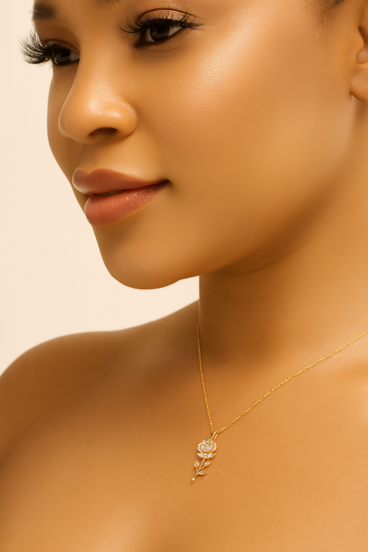 Close-up of a woman wearing a gold necklace with a floral pendant against a beige background