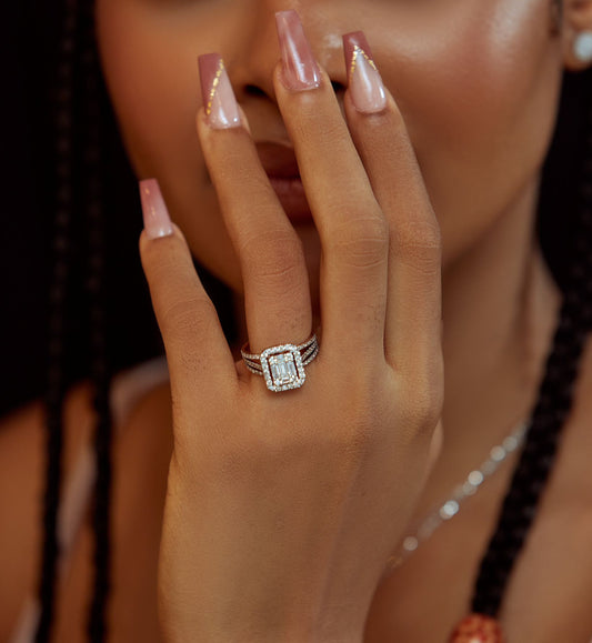 A person showcasing their engagement ring with an emerald cut moissanite gemstone, wearing it on a sterling silver band.