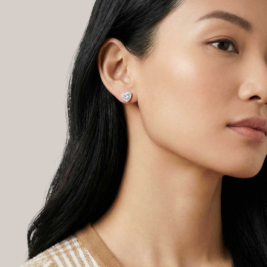 Close-up of a woman wearing diamond earrings with a neutral background