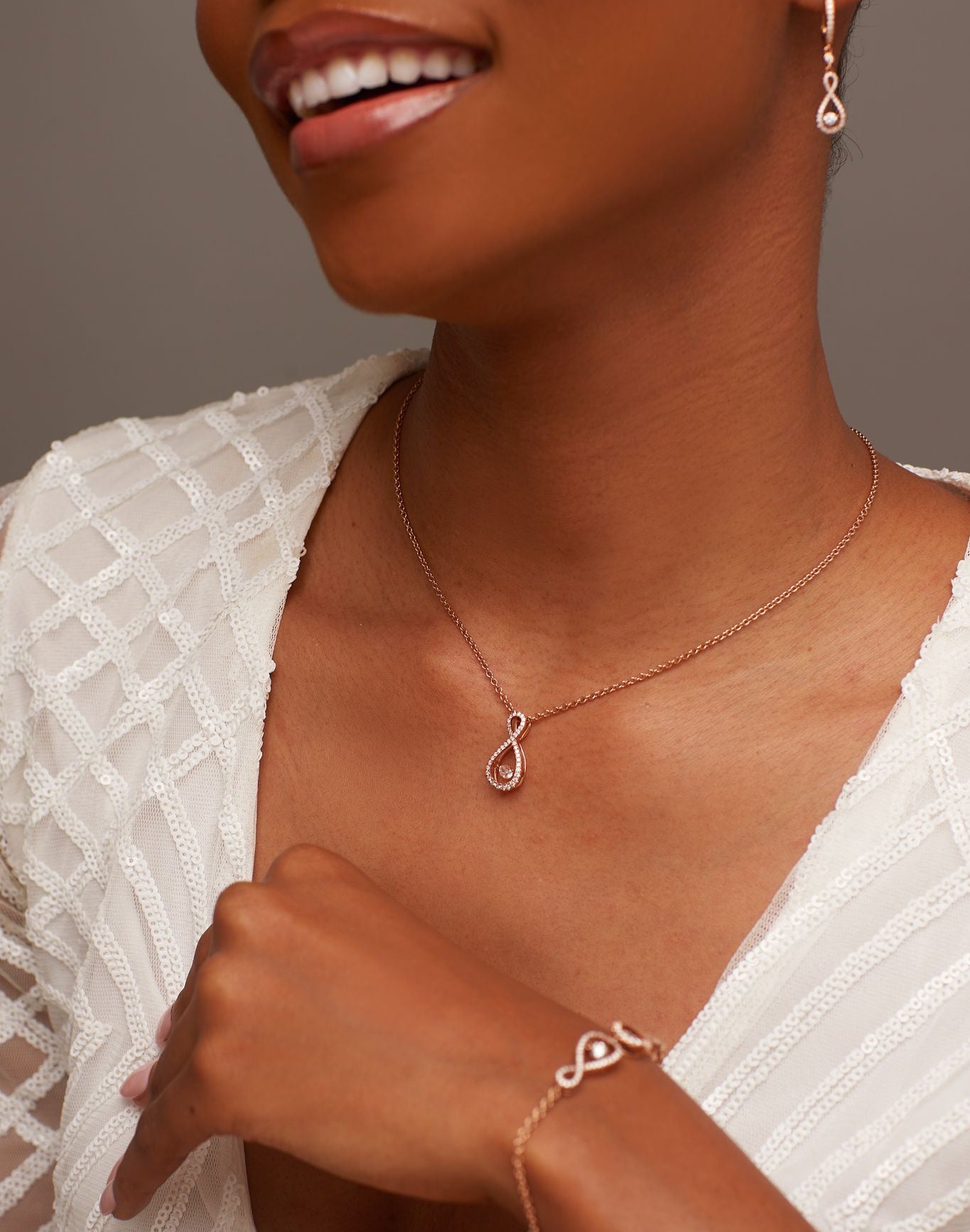 Woman wearing a gold necklace and bracelet with a neutral background