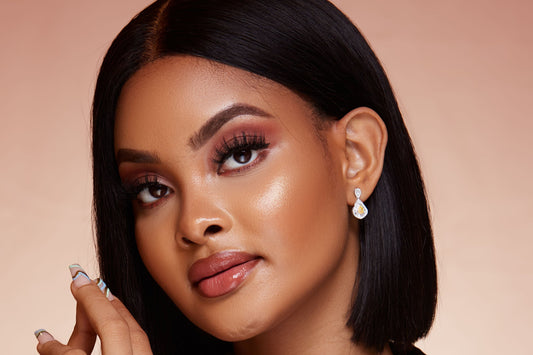 A woman with a natural hairstyle wearing 18K gold hoop earrings with a yellow diamond design.