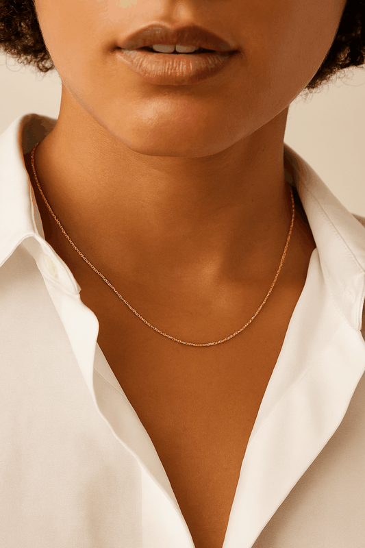 Close-up of a person wearing a gold necklace with a white shirt.