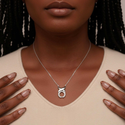 Silver necklace with a pendant worn by a person against a neutral background