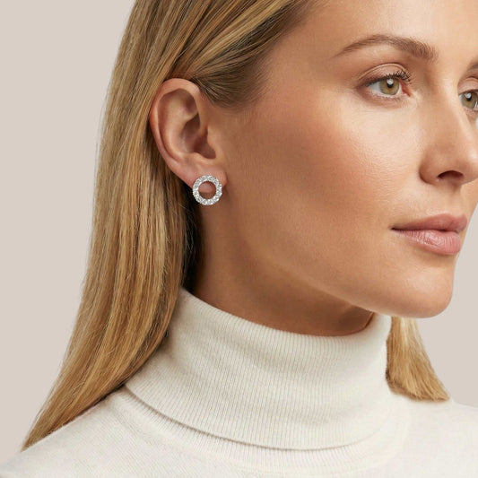 Close-up of a woman wearing a silver hoop earring against a light background