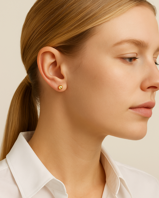 Close-up of a woman wearing gold earrings with a plain background