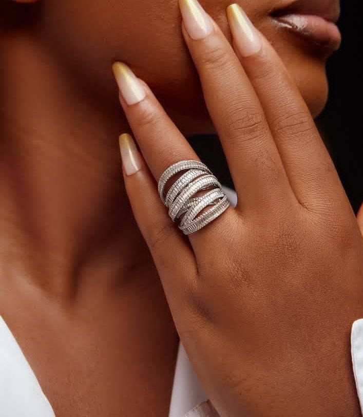 Close-up of a hand wearing multiple silver rings with a blurred background