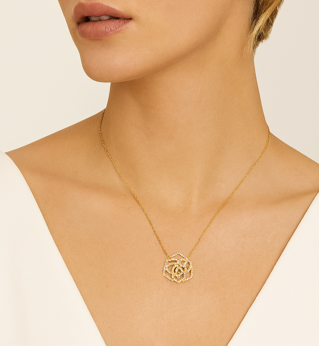Gold necklace with a rose pendant on a mannequin neck against a beige background