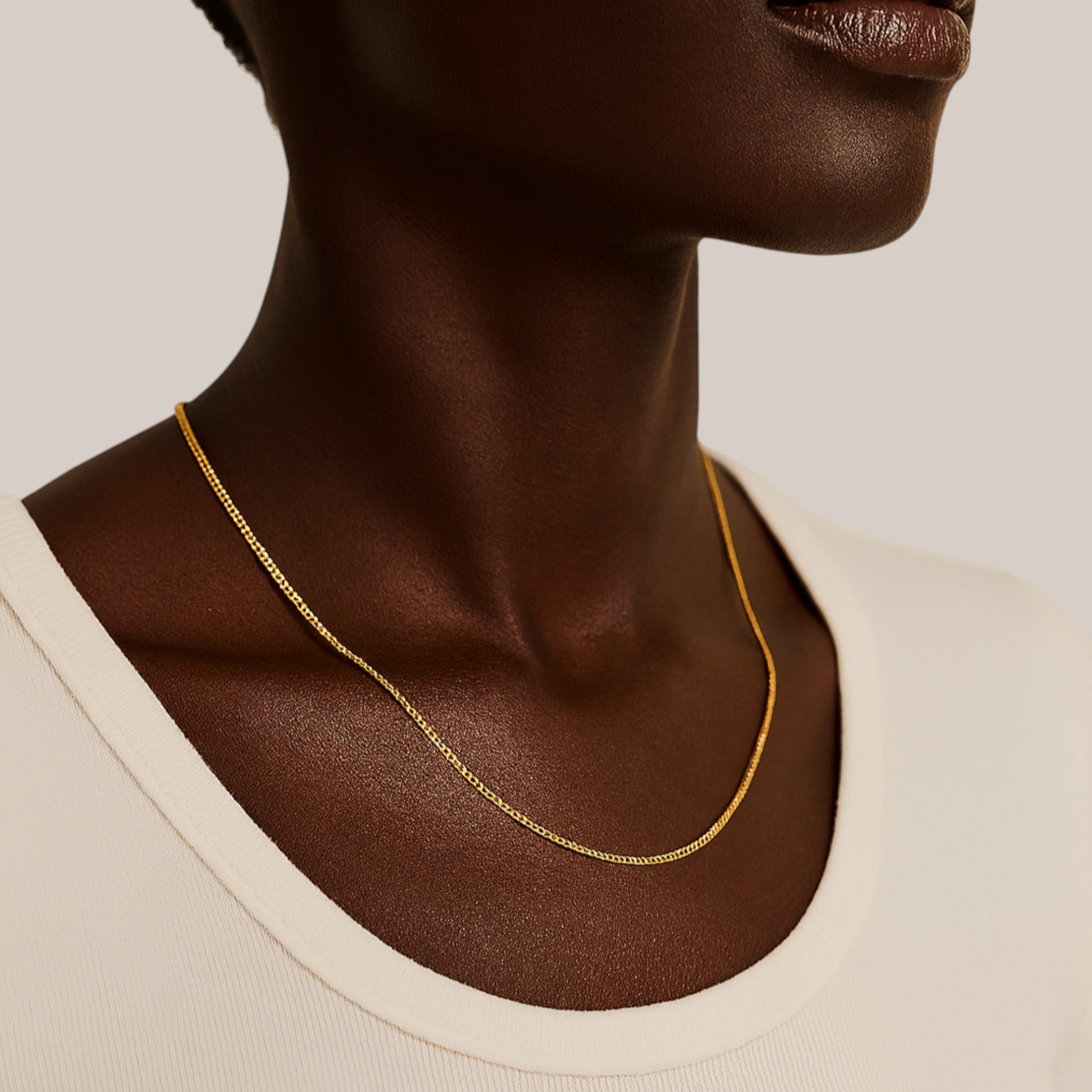 Gold necklace on a model against a neutral background