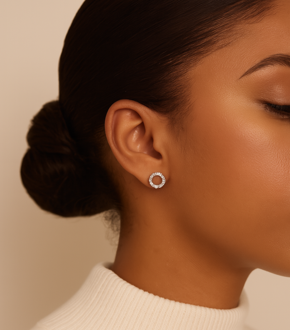 Close-up of a person wearing silver hoop earrings with a neutral background