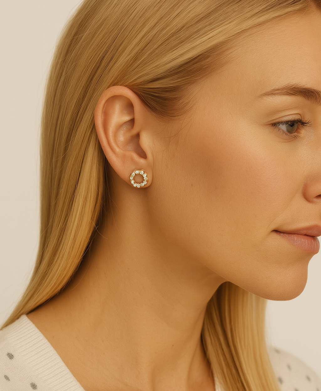 Close-up of a woman wearing gold hoop earrings with a neutral background
