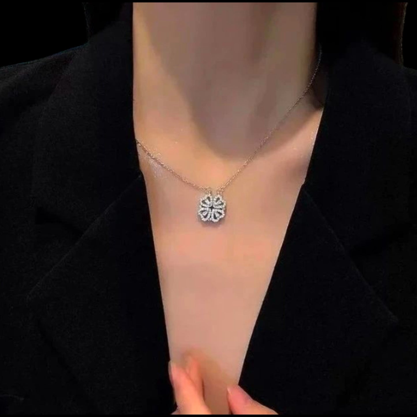 Necklace with a floral pendant on a person wearing a black blazer.