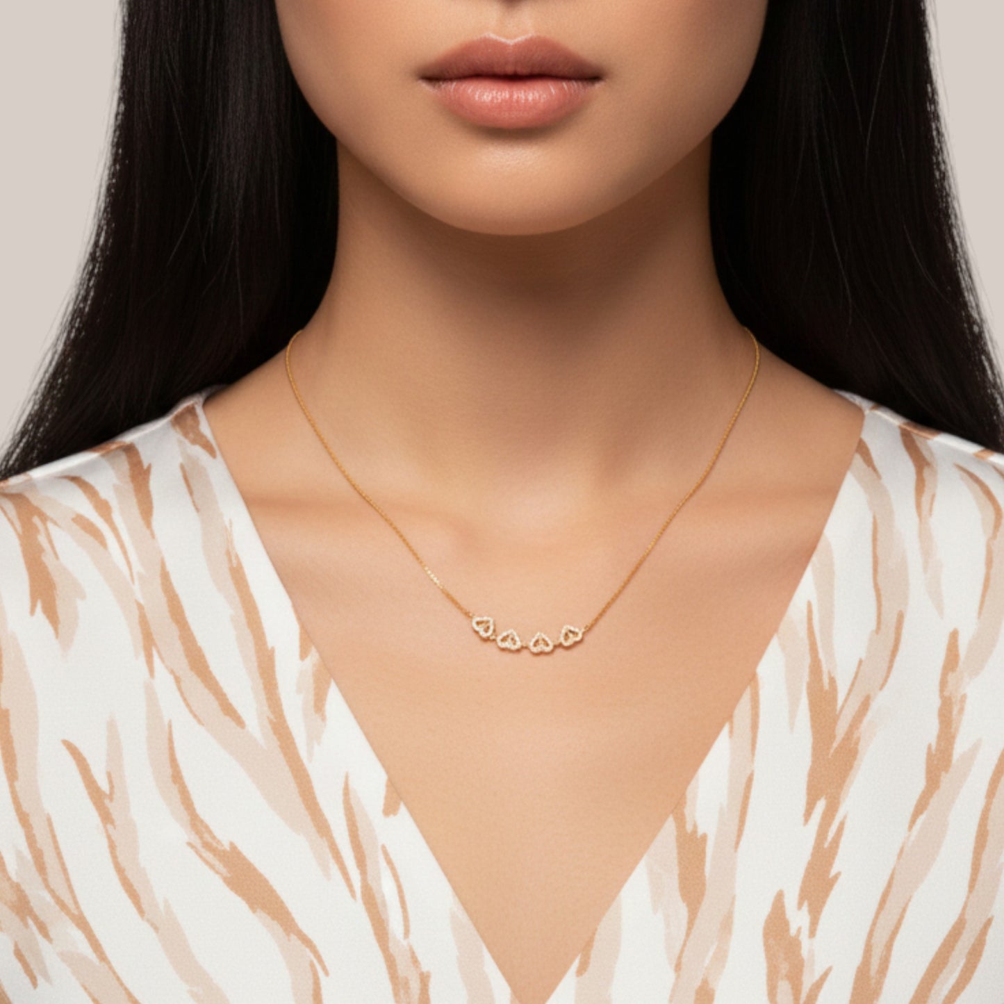 Close-up of a woman wearing a gold necklace with heart pendants on a neutral background