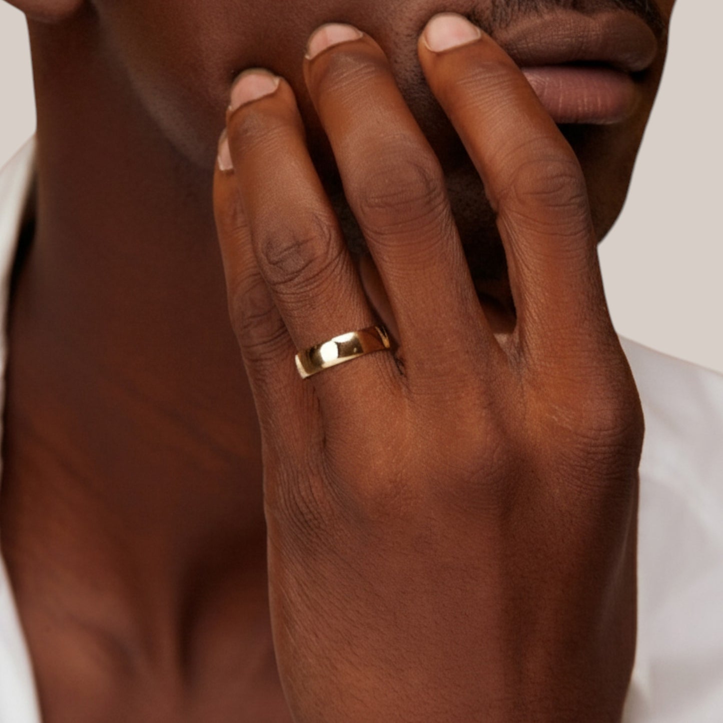 Hand wearing a gold ring with a neutral background