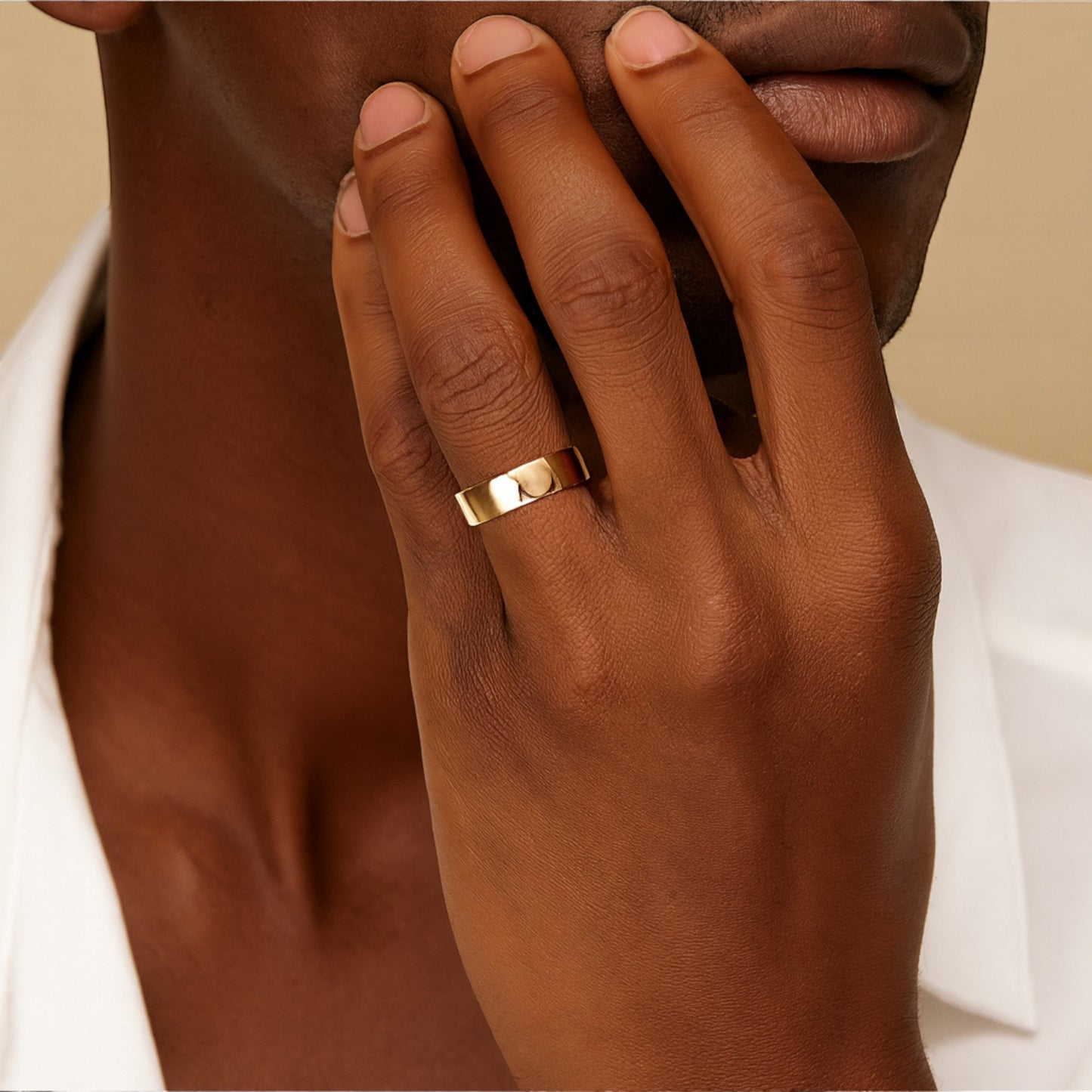 Hand wearing a gold ring with a neutral background