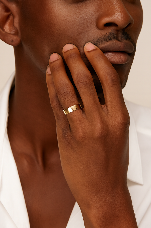 Close-up of a hand with a gold ring on a neutral background
