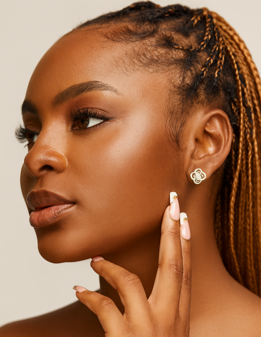 Woman with braided hair wearing gold earrings against a beige background