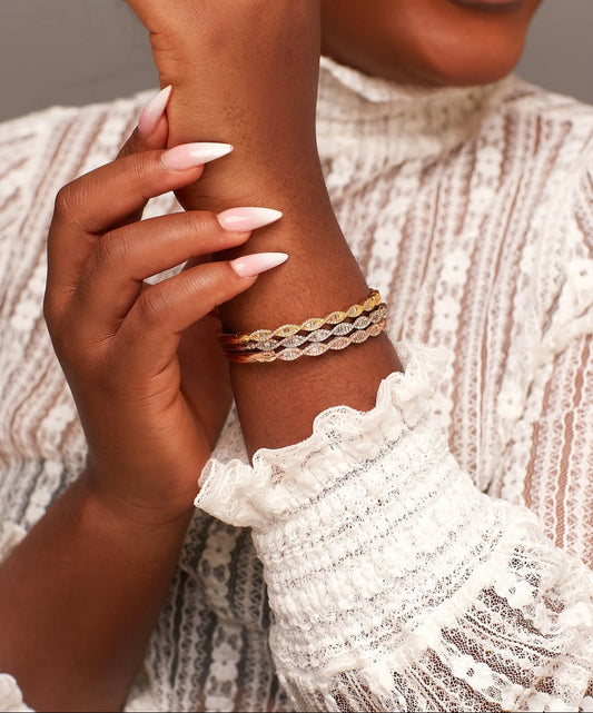 A person wearing an 18 karat gold bracelet with natural diamond accents on their wrist.