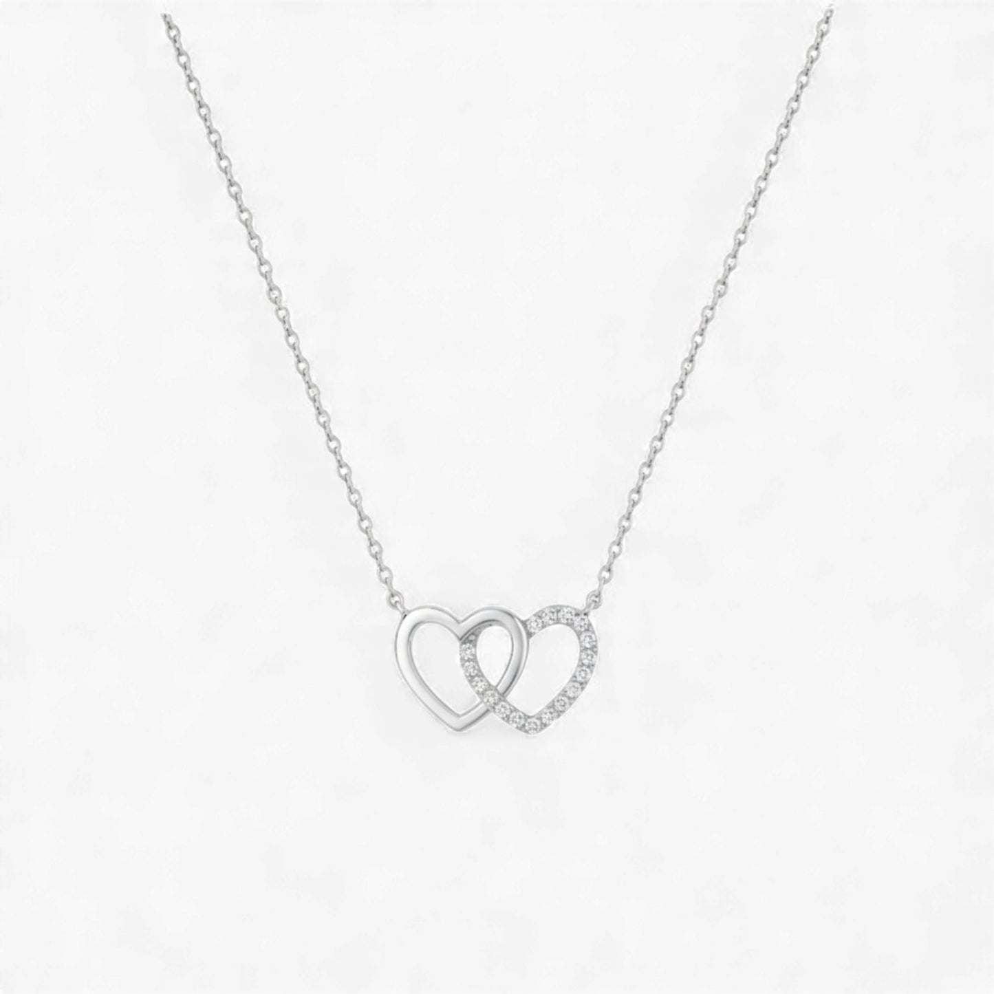 Silver necklace with interlocking heart pendants on a white background