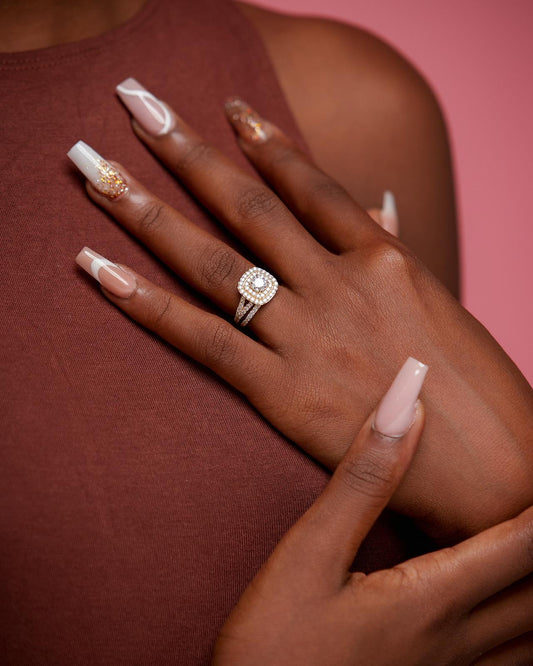 A person's hand showcasing a cushion cut moissanite ring with a sterling silver band. The ring is worn on the ring finger.