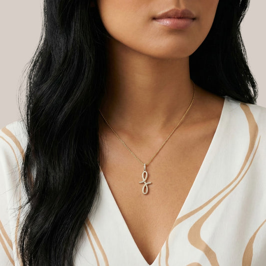 Woman wearing a gold necklace with an eye pendant against a neutral background