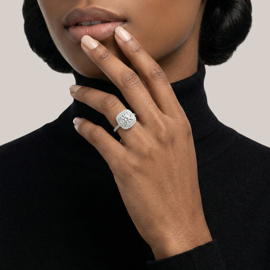 Hand wearing a diamond ring with a neutral background