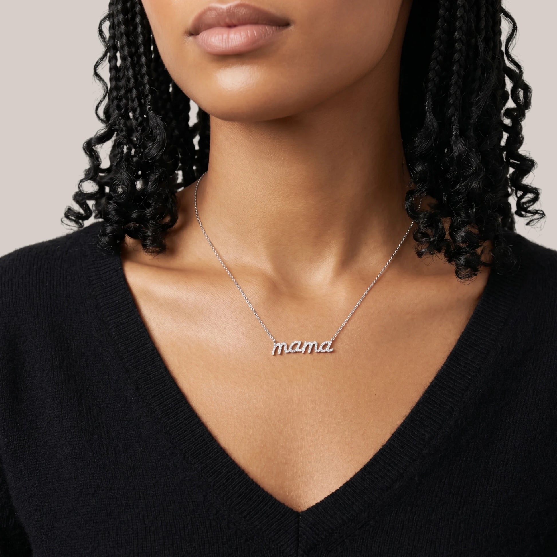 Necklace with 'mama' pendant worn by a person against a neutral background