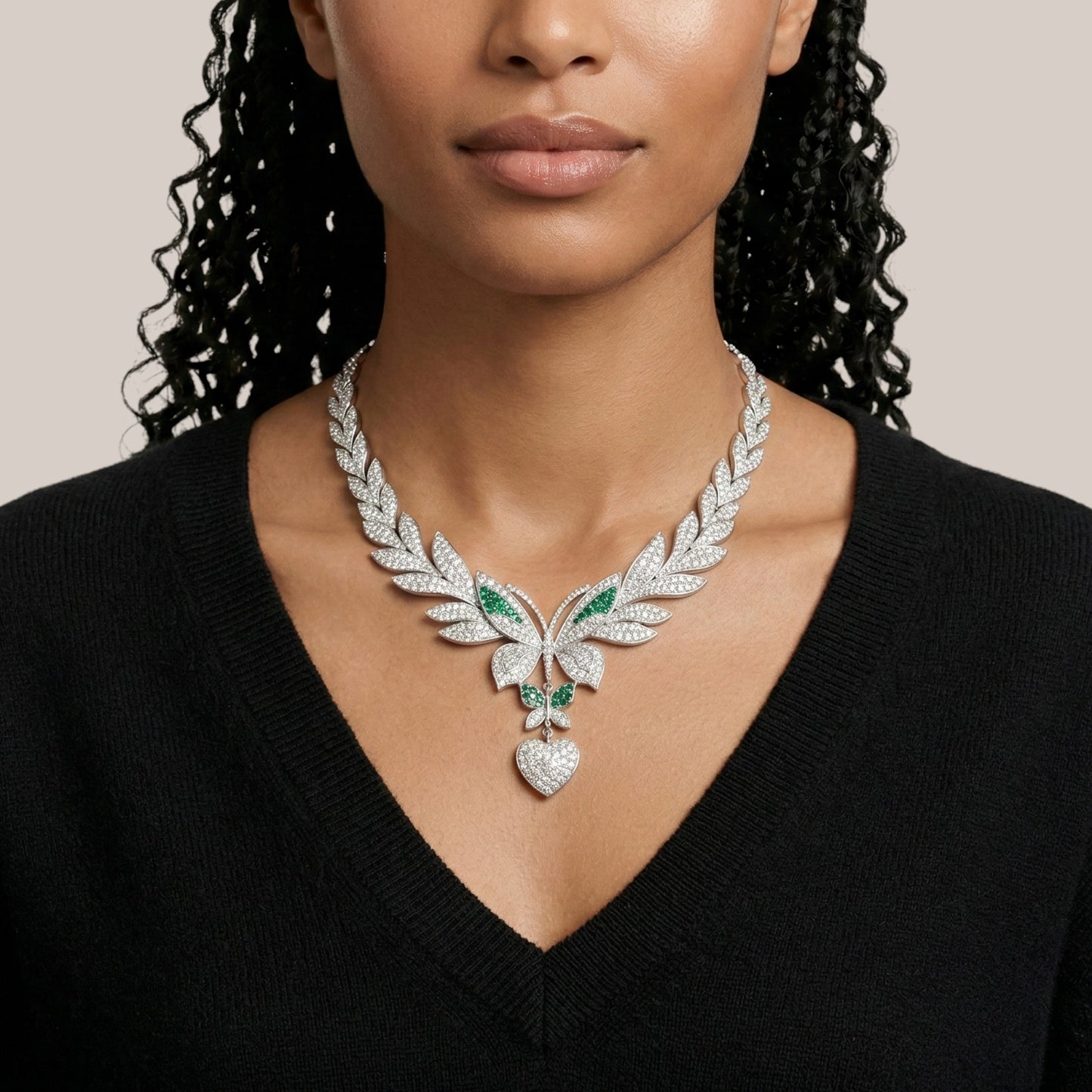 Woman wearing a luxurious diamond necklace with green gemstones on a neutral background