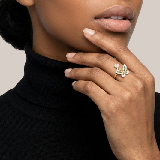 Close-up of a person wearing a ring with a green gemstone on a neutral background