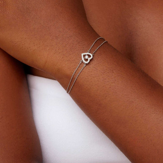 Silver bracelet with a heart-shaped clasp on a person's wrist