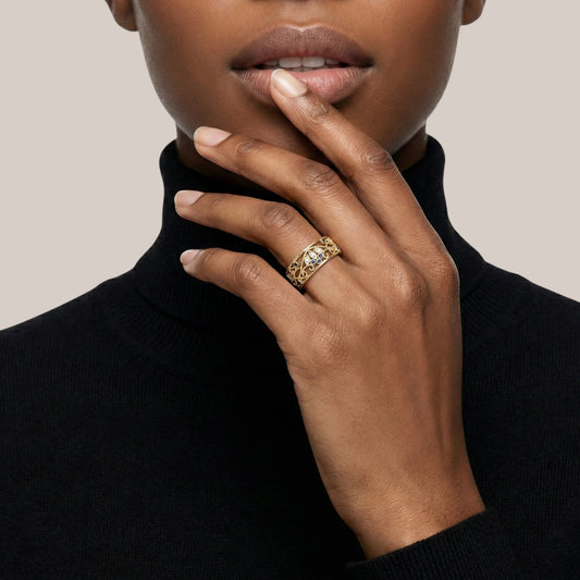 Close-up of a person wearing a gold ring on a plain background