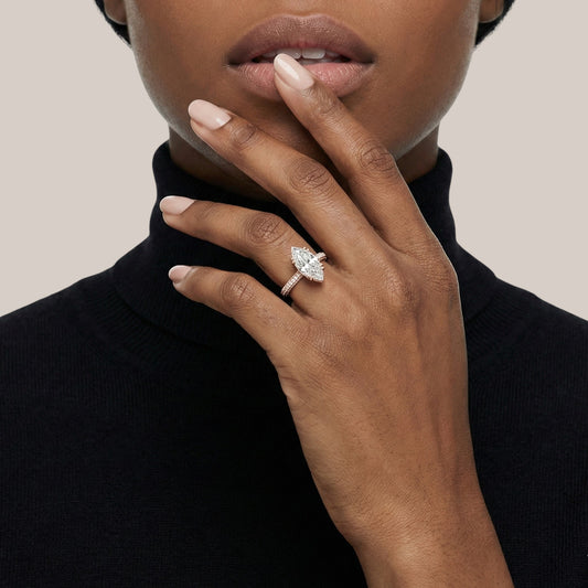 Hand wearing a diamond ring with a neutral background