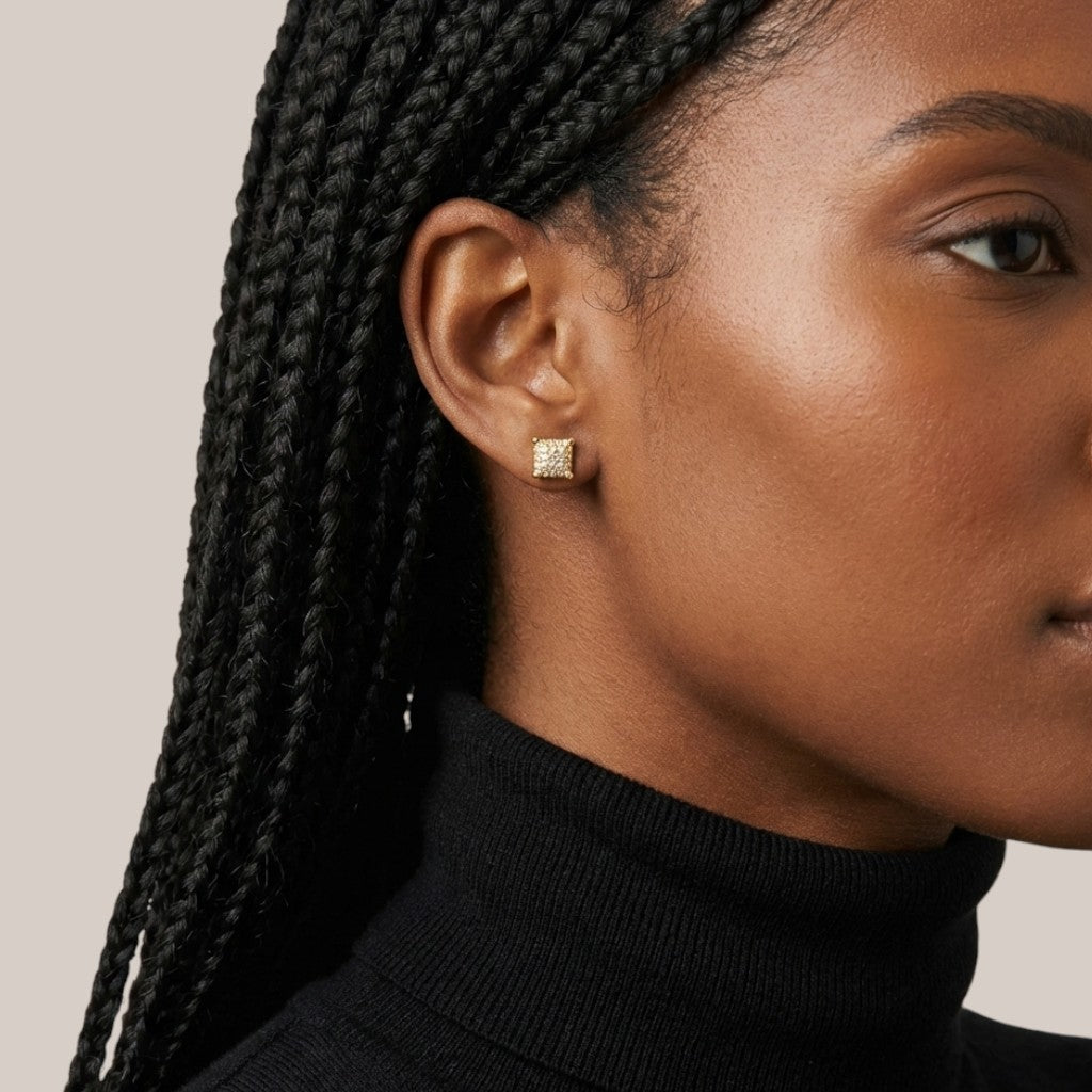 Close-up of a person wearing a gold earring with a beige background