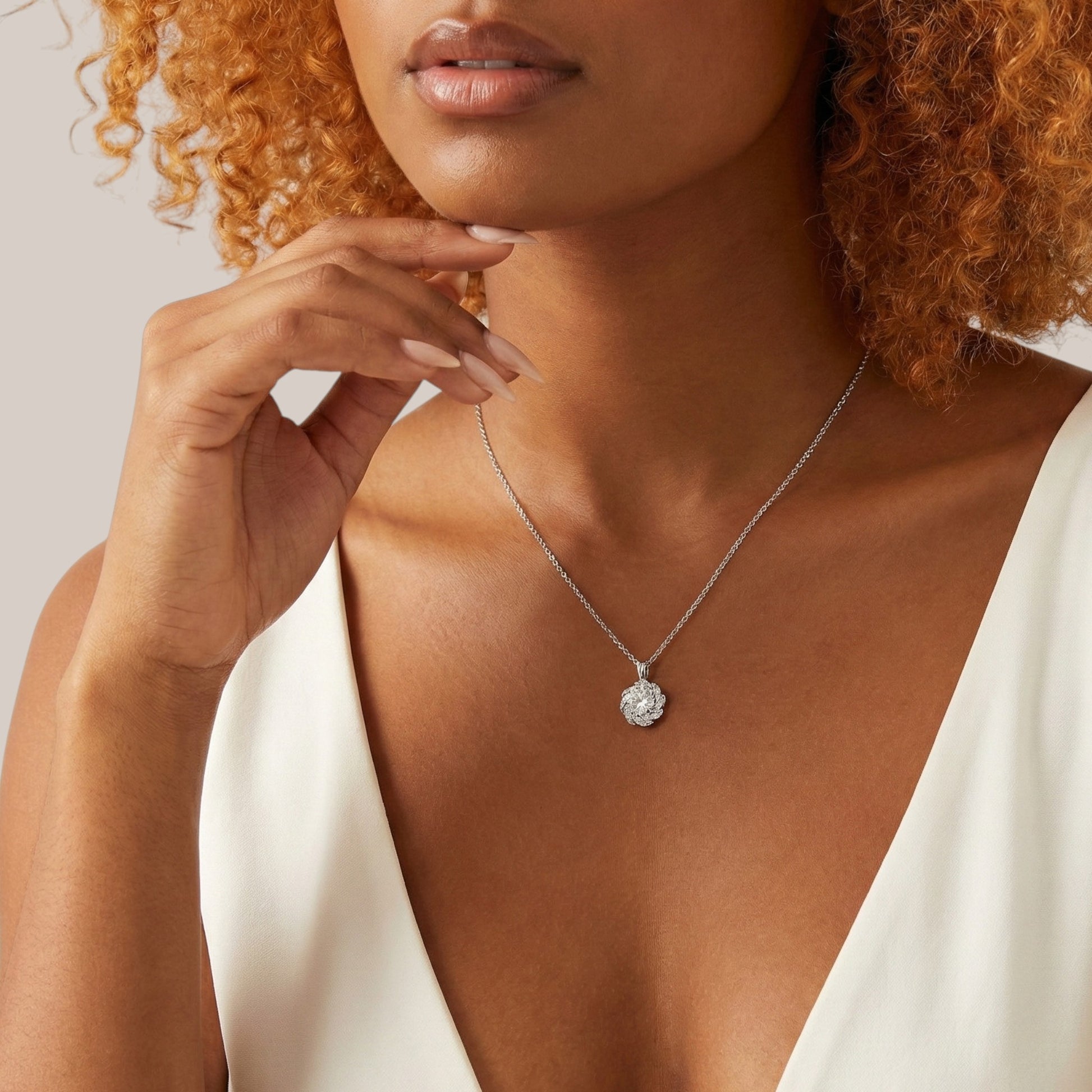 Woman wearing a silver necklace with a pendant against a neutral background