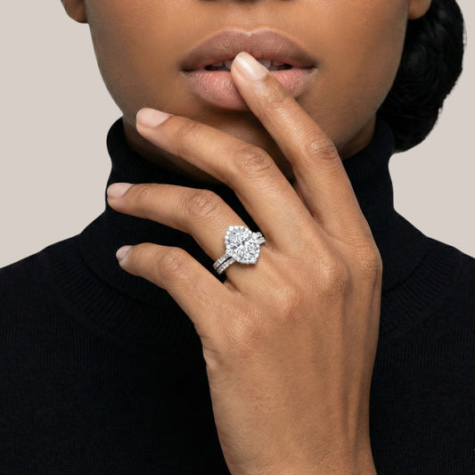 Close-up of a hand wearing a diamond ring with a neutral background