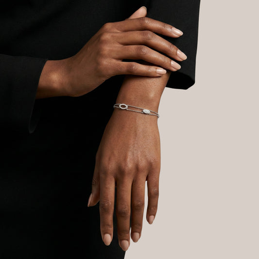Close-up of a person's wrist wearing a silver bracelet on a neutral background