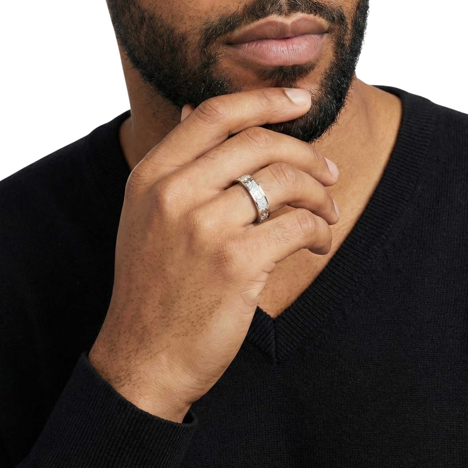 Man wearing a black sweater with a close-up of his hand and ring.