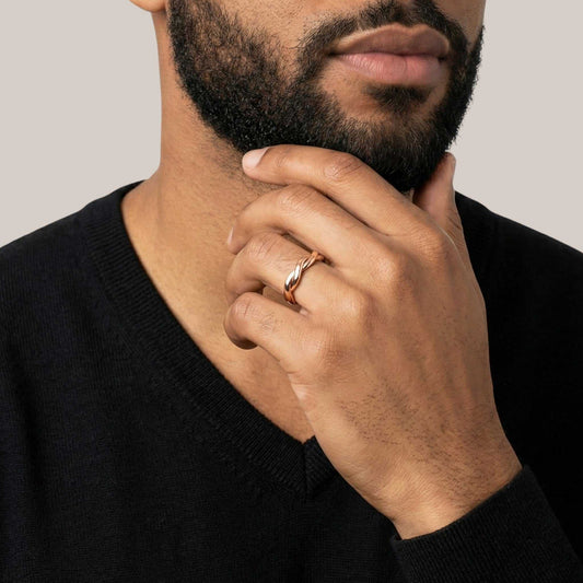 Man wearing a gold ring on his finger with a neutral background