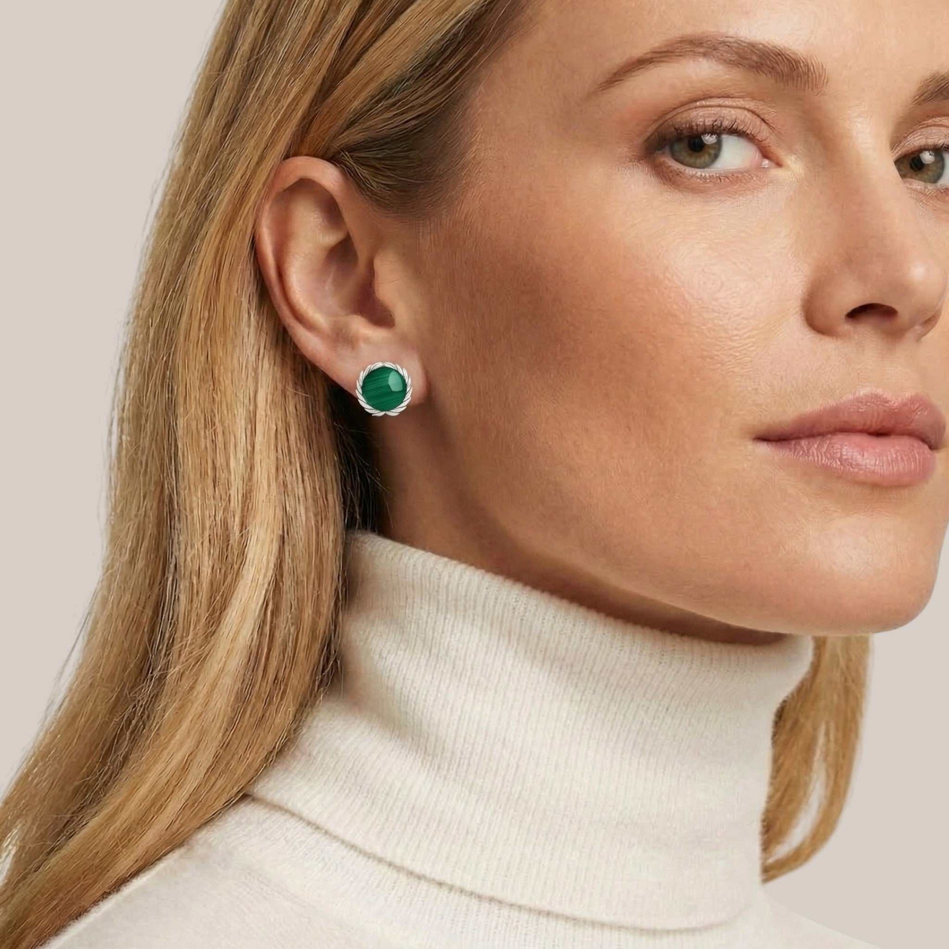 Close-up of a woman wearing green gemstone earrings with a neutral background