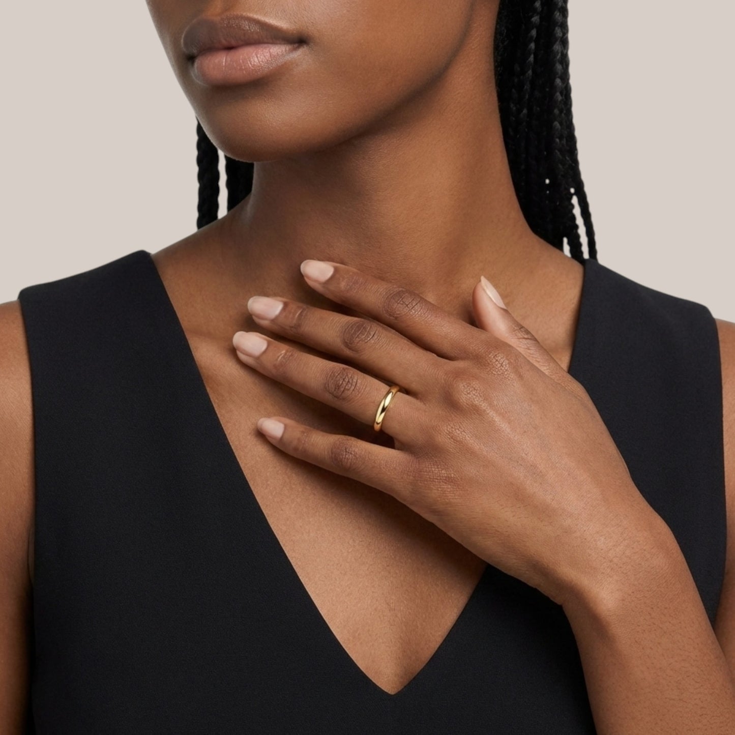 Woman wearing a gold ring on her hand with a neutral background